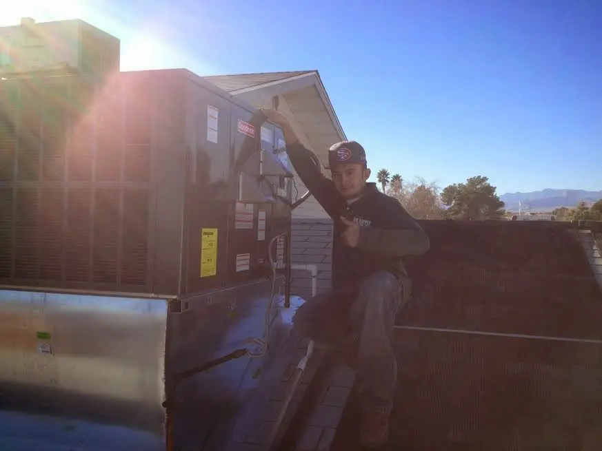 HVAC technician performing Air Duct Cleaning on a rooftop unit in Olathe